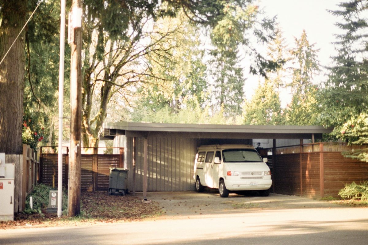Weißer Van unter einem überdachten Carport-Stellplatz in einer Wohnstraße
